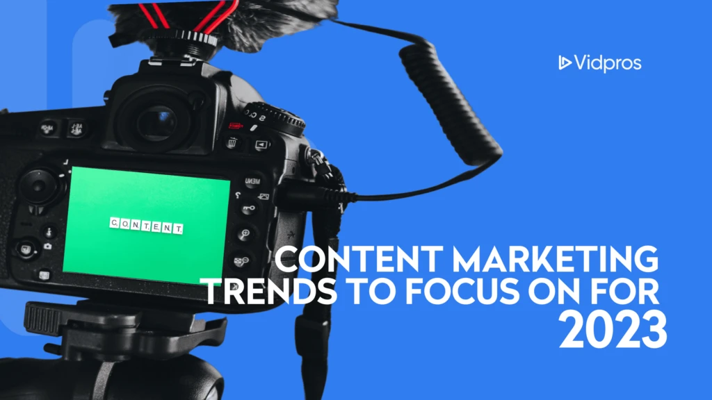 A DSLR camera with a microphone is focused on a screen displaying the word CONTENT in white on a green background. The text Content Marketing Trends to Focus on for 2023 is overlaid in bold white letters, highlighting insights for content creators. Vidpros logo is in the top right corner.